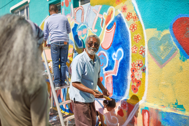 Senior man paints colorful community mural